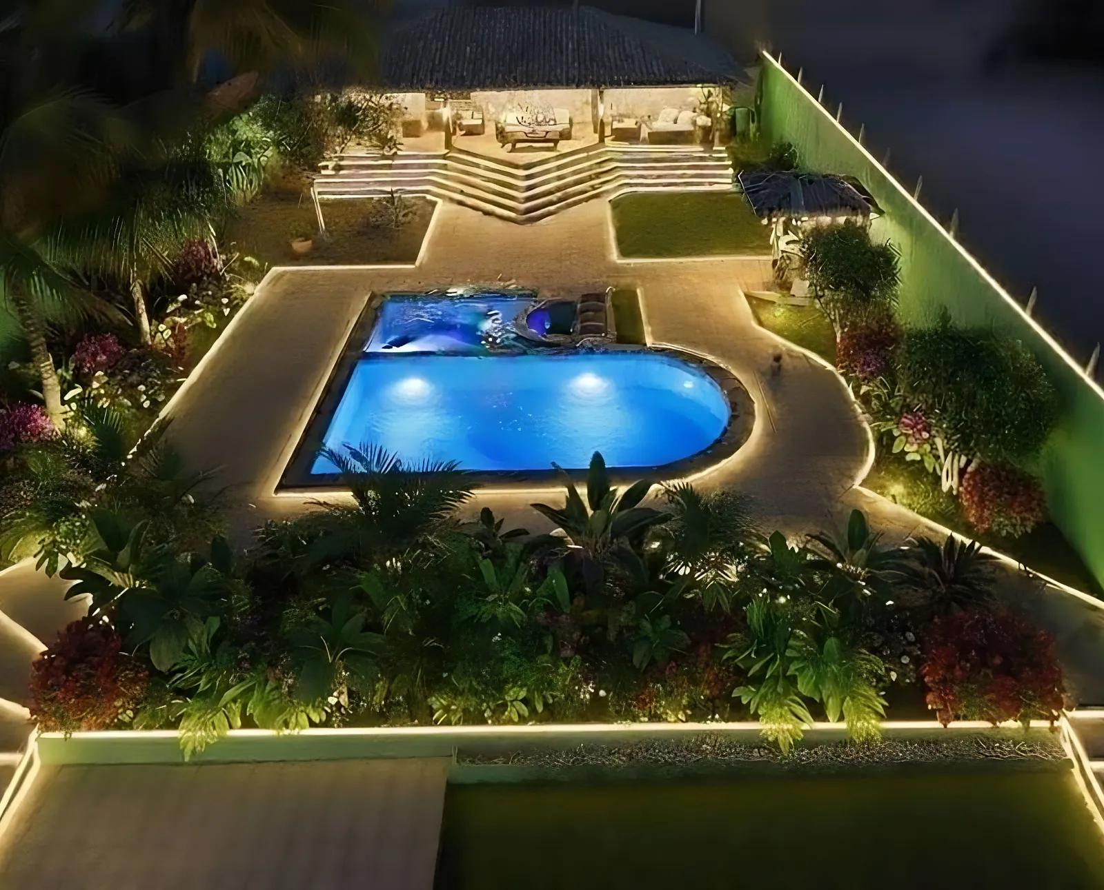 Projeto da área de lazer à noite: piscina iluminada, luz de contorno nos caminhos e paisagismo tropical
