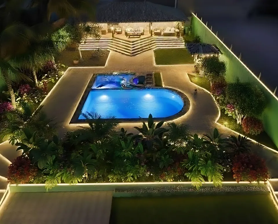 Projeto da área de lazer à noite, com luz de contorno e paisagismo tropical